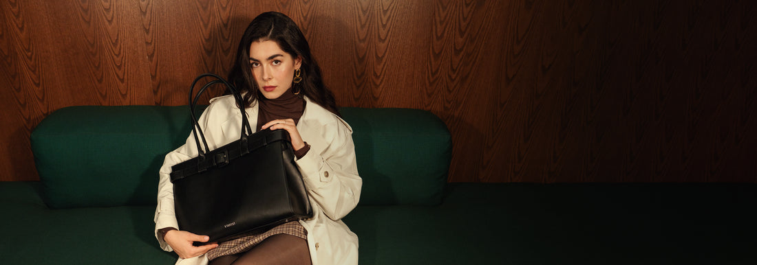 Banner of a woman seated on a green couch holding a black tote bag in her hands.